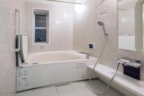 a white bathroom with a tub and a shower at L -scene Centrally located in Matsumoto Maximum 8 people 2 min walk from Matsumoto Castle in Matsumoto