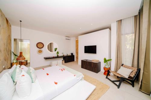 a bedroom with a large white bed and a chair at Ycona Eco-Luxury Resort, Zanzibar in Dikoni