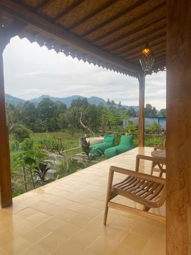 a porch with a bench and a view of the mountains at Green vanilla kabin in Silebeng