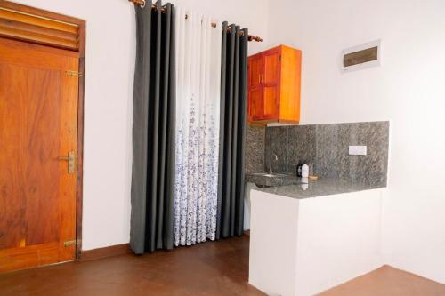 cocina con encimera, fregadero y puerta en Dunitha Villa - Surrounded by Greenery, en Dikwella