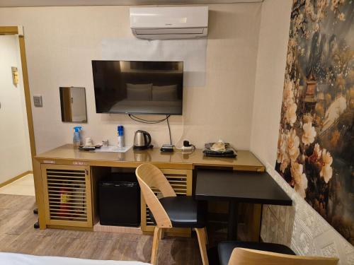 a desk in a hotel room with a tv on the wall at New Day Hotel Gangnam in Seoul