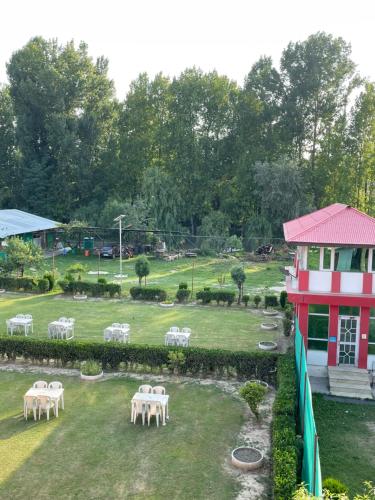 a garden with white tables and a red and white building at New Sahil in Srinagar