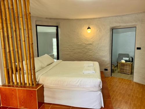 a bedroom with a large bed with bamboo poles at บ้านดิน 2 ชั้น in Khanong Phra