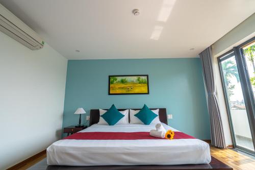 a bedroom with a large bed with blue walls at Golden Star Villa Hoi An in Hoi An