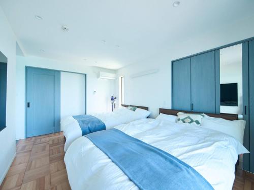 a bedroom with two white beds and a television at Blue Ocean Awaji in Sumoto