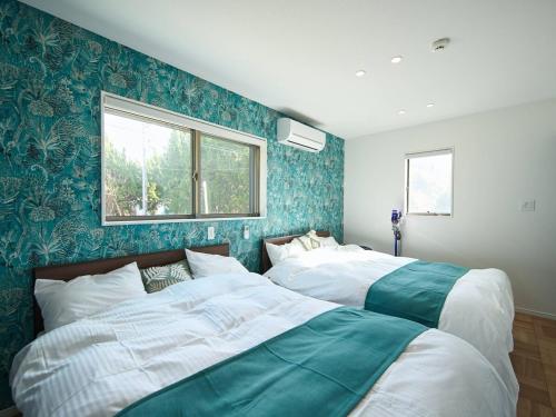 two beds in a bedroom with blue and green wallpaper at Blue Ocean Awaji in Sumoto