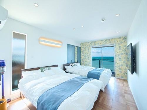 two beds in a room with a view of the ocean at Blue Ocean Awaji in Sumoto