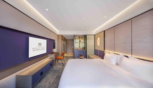a hotel room with a large bed and a tv at New Century Mansion Hotel Nanxun Shuijingjing in Huzhou