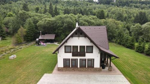 a white house with a brown roof on a grass field at Mountain Paradise & Wellness in Izvoare