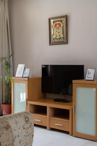 a living room with a television on a wooden entertainment center at Krishnalaya Mansion by VEO - Part of StayVista in Jaipur