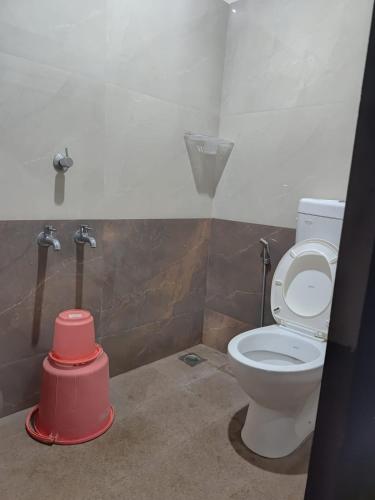 a bathroom with a toilet and a red bucket at Suvarna TOURIST HOME in Dharmastala