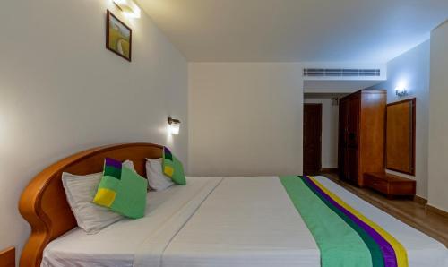 a bedroom with a large white bed with colorful pillows at Treebo Sadhoo Heritage in Kannur