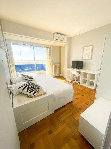 une chambre avec un lit et une grande fenêtre dans l'établissement Appartement Promenade des Anglais, à Nice