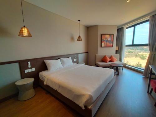 Un dormitorio con una gran cama blanca y una ventana. en Mandala Coast Chambay Bình Thuận, en Ấp Nhơn Long
