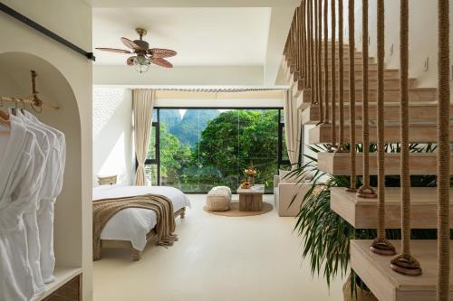 a bedroom with a bed and a large window at Yangshuo OrangeWhite Resort - An Exclusive Cave - Inspired Haven by the River - Featuring Panoramic Mountain Views-Infinity Pool & Alpaca Encounters & Tailor-Made Excursions in Yangshuo