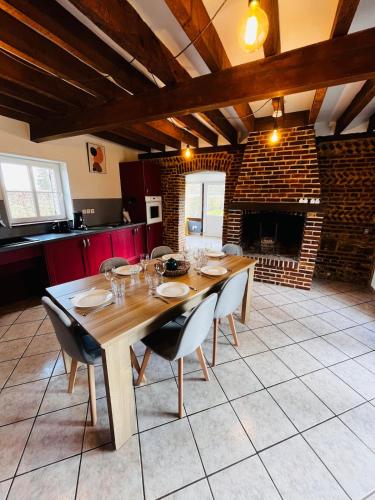 une salle à manger avec une table en bois et une cheminée dans l'établissement Maison de vacances Gîte de charme Le cellier, à Boissay
