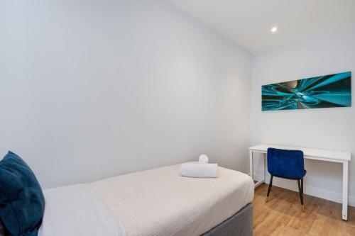 a bedroom with a bed and a blue chair at Luxury 5 Bedroom, 4 Bathroom Home in Purley in Purley