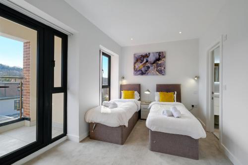 two beds in a room with large windows at Luxury 5 Bedroom, 4 Bathroom Home in Purley in Purley