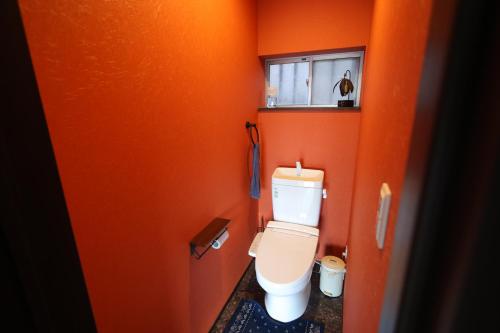 a bathroom with a toilet in an orange wall at 火口に最も近い桜島のゲストハウスikoてらす in Kagoshima