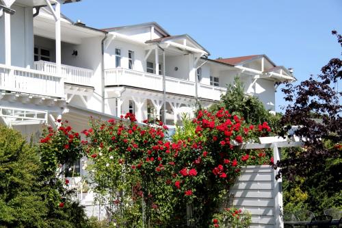 a white building with red flowers in front of it at AKZENT Waldhotel Spa Rügen in Göhren