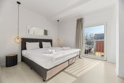 ein Schlafzimmer mit einem großen Bett und einem großen Fenster in der Unterkunft MoHost Harmony Apartments - Brasov City Center in Braşov