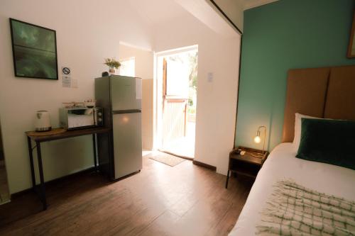 a room with a refrigerator and a bed and a door at Die Stalle in Klerksdorp