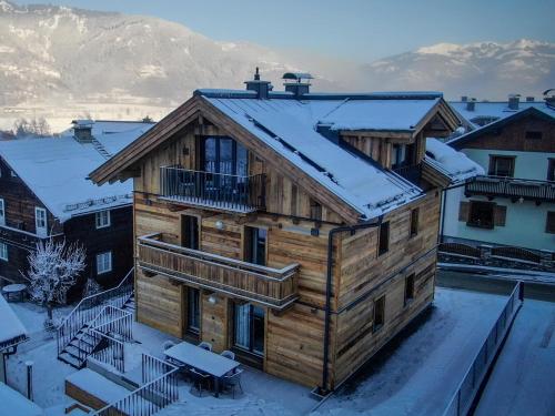 a large wooden house with snow on the roof at Chalet Alpenglück by Kaprun Rentals in Kaprun