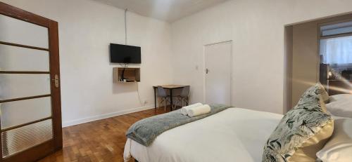 a bedroom with a bed and a tv on the wall at Carrington Guesthouse in Kimberley
