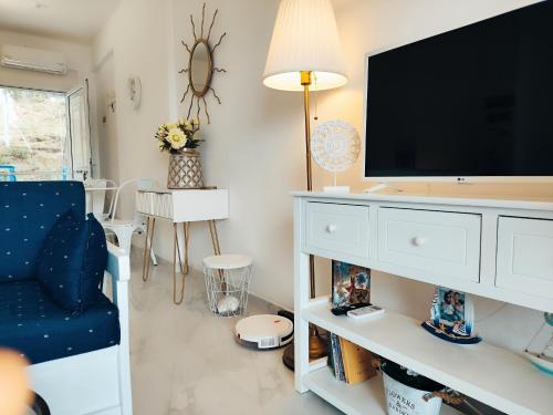 a living room with a tv and a blue chair at Siviri Sea & Forest-Cozy Apartment with Garden & Nature Views in Siviri