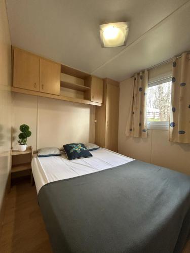 Cette petite chambre dispose d'un grand lit et d'une fenêtre. dans l'établissement Séjour Idéal en Mobil-home 6 à 8 Personnes, à Pont-de-Salars