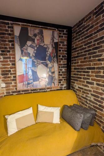- un canapé jaune dans une pièce dotée d'un mur en briques dans l'établissement Studio écologique, à Paris