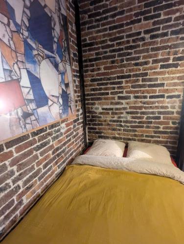 - une chambre dotée d'un mur en briques et d'un lit dans l'établissement Studio écologique, à Paris