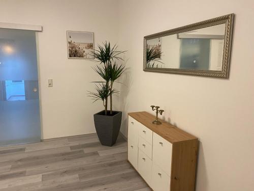 a room with a mirror and a dresser and a plant at Haus Schönborn Norden Family in Norden