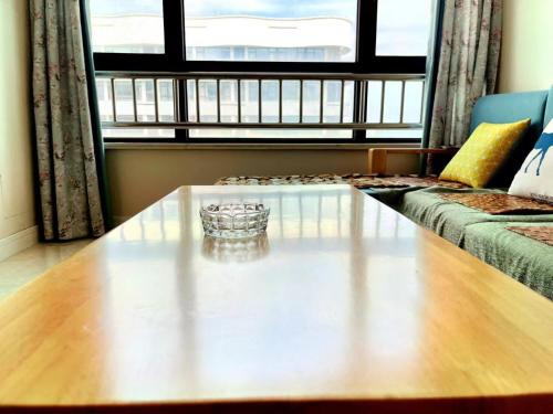 a living room with a coffee table in front of a window at JiuJiu Binhai Hotel in Huangdao