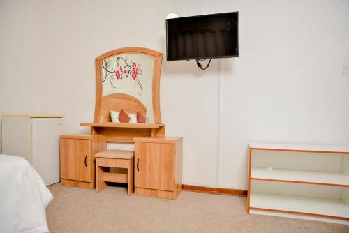 a room with a chair and a desk and a tv at Crystal Palace Hotel in Gaborone