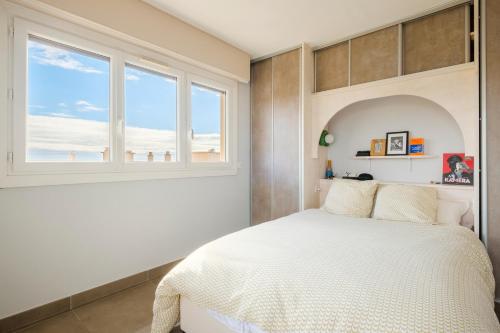 une chambre avec un lit blanc et une fenêtre dans l'établissement Appartement Les Amandiers, à Cagnes-sur-Mer