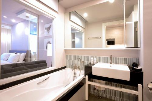 Un baño con una gran bañera blanca y un lavabo. en THE KANNAS Hotel & Serviced Apartment, Chiang Mai SHA Certified, en Chiang Mai