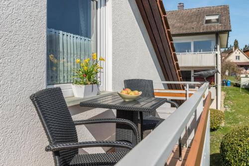 a balcony with two chairs and a table with a bowl of fruit at Ferienwohnung Roth in Überlingen