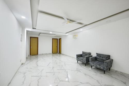 a room with two chairs and a ceiling fan at FabHotel Luxe 8 Stayz - Phase 1 Metro, Golf Course Road & Arjun Marg in Gurgaon