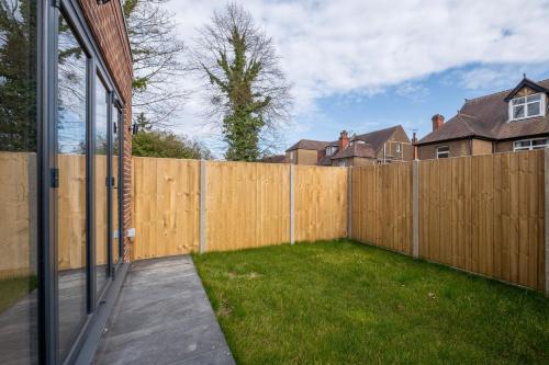 a backyard with a wooden fence and a green yard at Luxury 5 Bedroom, 4 Bathroom Home in Purley in Purley