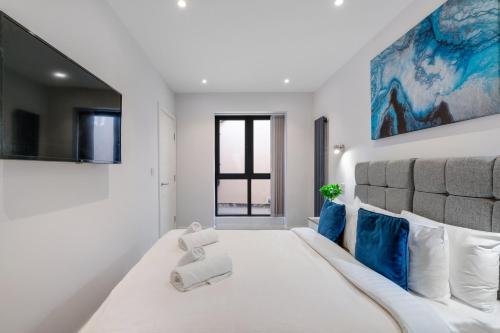 a white bedroom with a large bed with blue pillows at Luxury 5 Bedroom, 4 Bathroom Home in Purley in Purley