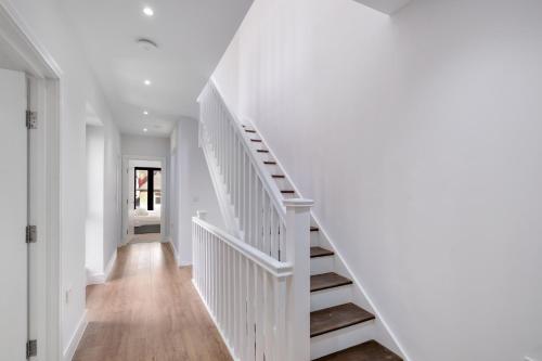 a white staircase in a home with white walls and wooden floors at Luxury 5 Bedroom, 4 Bathroom Home in Purley in Purley