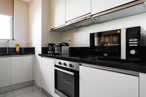 a kitchen with black counter tops and a microwave at Simply Comfort Vacation Homes Rental Luxury 2Br Apt Stunning Views in Amna Tower in Dubai