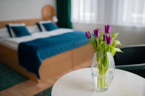 a vase of purple flowers on a table in a bedroom at Hotel Na Pekárně in Sušice