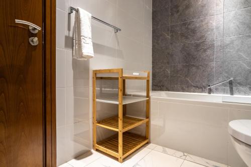 a bathroom with a wooden shelf next to a bath tub at Simply Comfort Vacation Homes Rental Luxury 2Br Apt Stunning Views in Amna Tower in Dubai