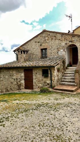 a stone building with a door and stairs in front at Agriturismo Le Querciole in Val d'Orcia in Bagno Vignoni
