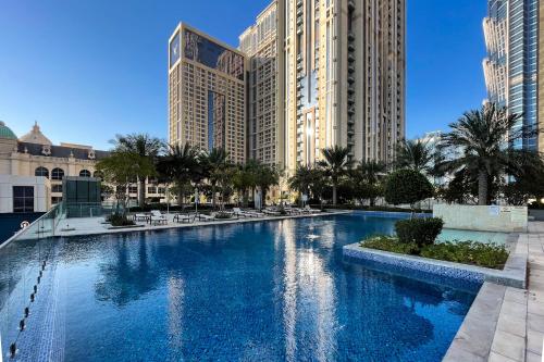 a large swimming pool in a city with tall buildings at Simply Comfort Vacation Homes Rental Luxury 2Br Apt Stunning Views in Amna Tower in Dubai