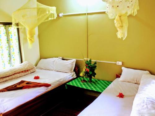 two beds in a room with a green table at Bardia Riverside View Park Resort - FR and EN speaking in Bhurkīā