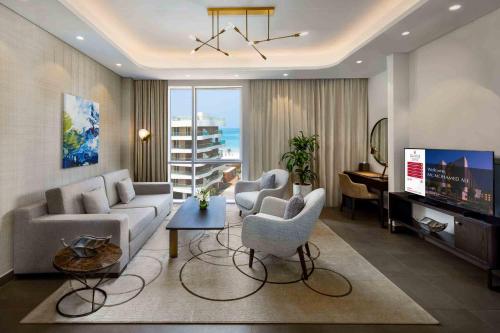 a living room with a couch and chairs and a television at Millennium Residences Saadiyat Island in Ḩayl