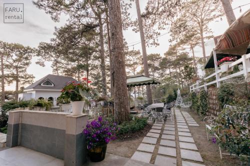 a garden with flowers and a house at Faru Pine Woods Villa in Xuan An